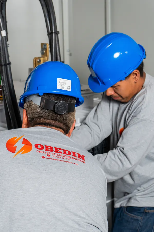 Dos técnicos de OBEDIN trabajan en las conexiones junto al transformador